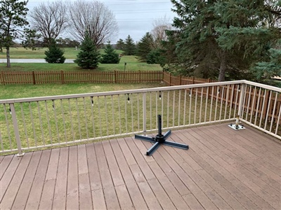 Before image of a wooden deck with railing overlooking a grassy backyard, trees, and open field, with a patio umbrella stand on the deck floor in White Bear Lake.