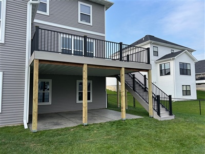 Two-story composite deck with stair access and black railings in Apple Valley backyard