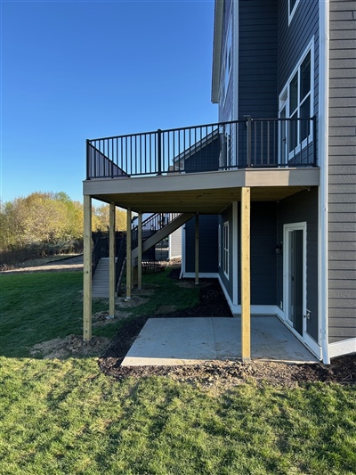 Under-deck area with concrete patio and exposed support structure on Long Lake residential deck